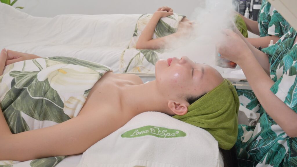 Bước xông hơi mặt với luồng hơi ấm phủ lên vùng da trước khi làm sạch sâu — Phòng khám Chuyên khoa Da liễu Lona Skin Lab, Cần Thơ