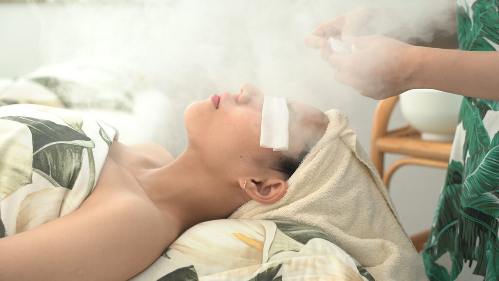 Khách nằm thư giãn trong phòng trị liệu với khăn quấn đầu, ánh sáng dịu — Phòng khám Chuyên khoa Da liễu Lona Skin Lab, Cần Thơ